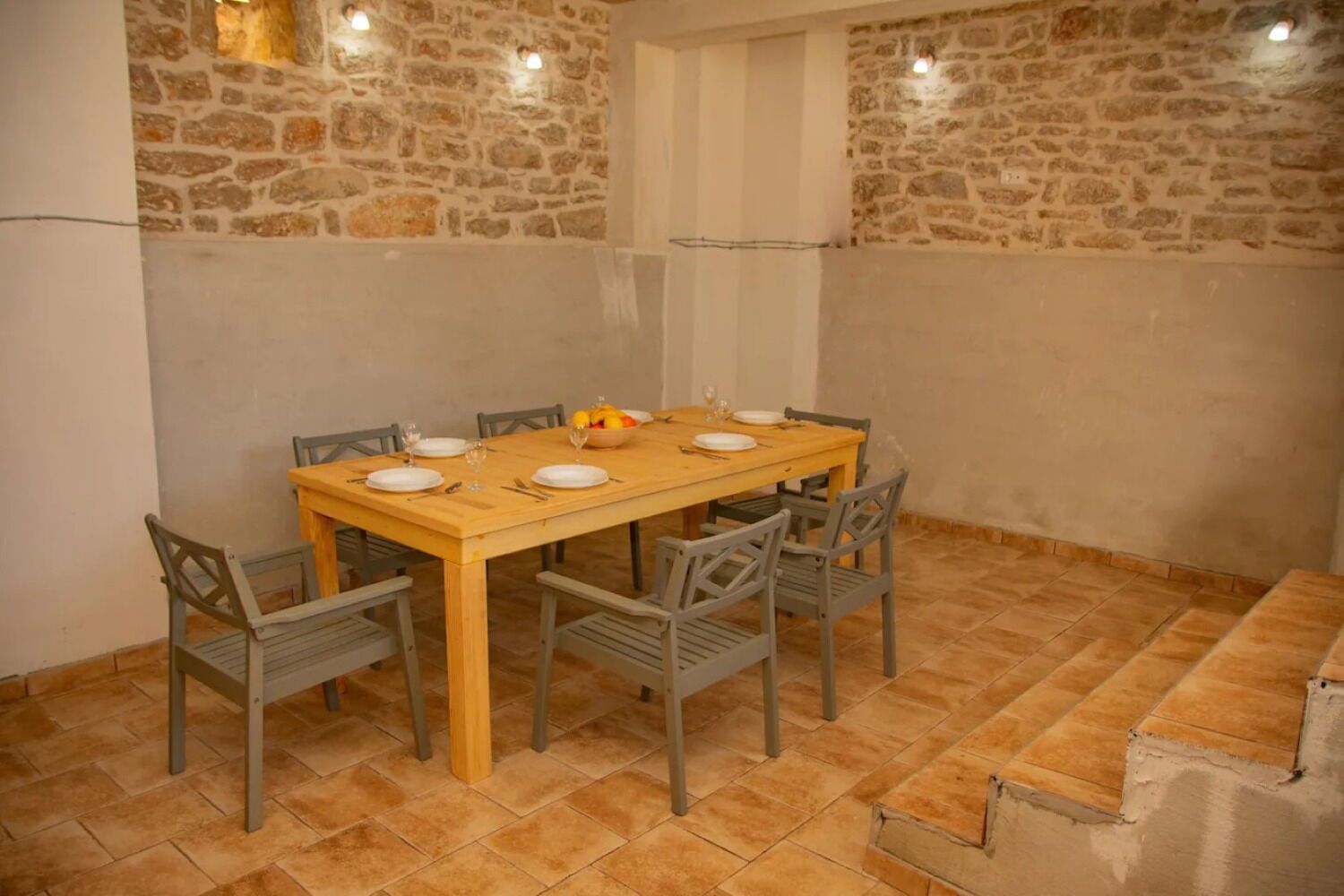 A dining area with a wooden table set for four, surrounded by six chairs.