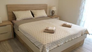 A neatly made bed with a polka dot bedspread and two folded towels on the side. - Apartment Mirella (Umag)