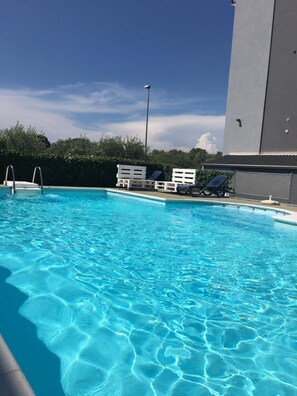 Una piscina al aire libre, tumbonas