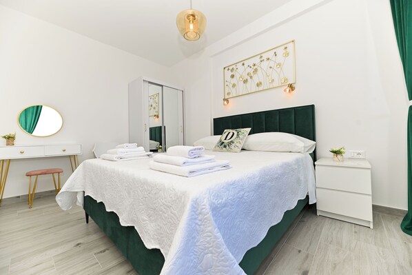 A neatly arranged bedroom with a bed, bedside tables, a desk, and a mirror. - Apartments Diva (Okrug)