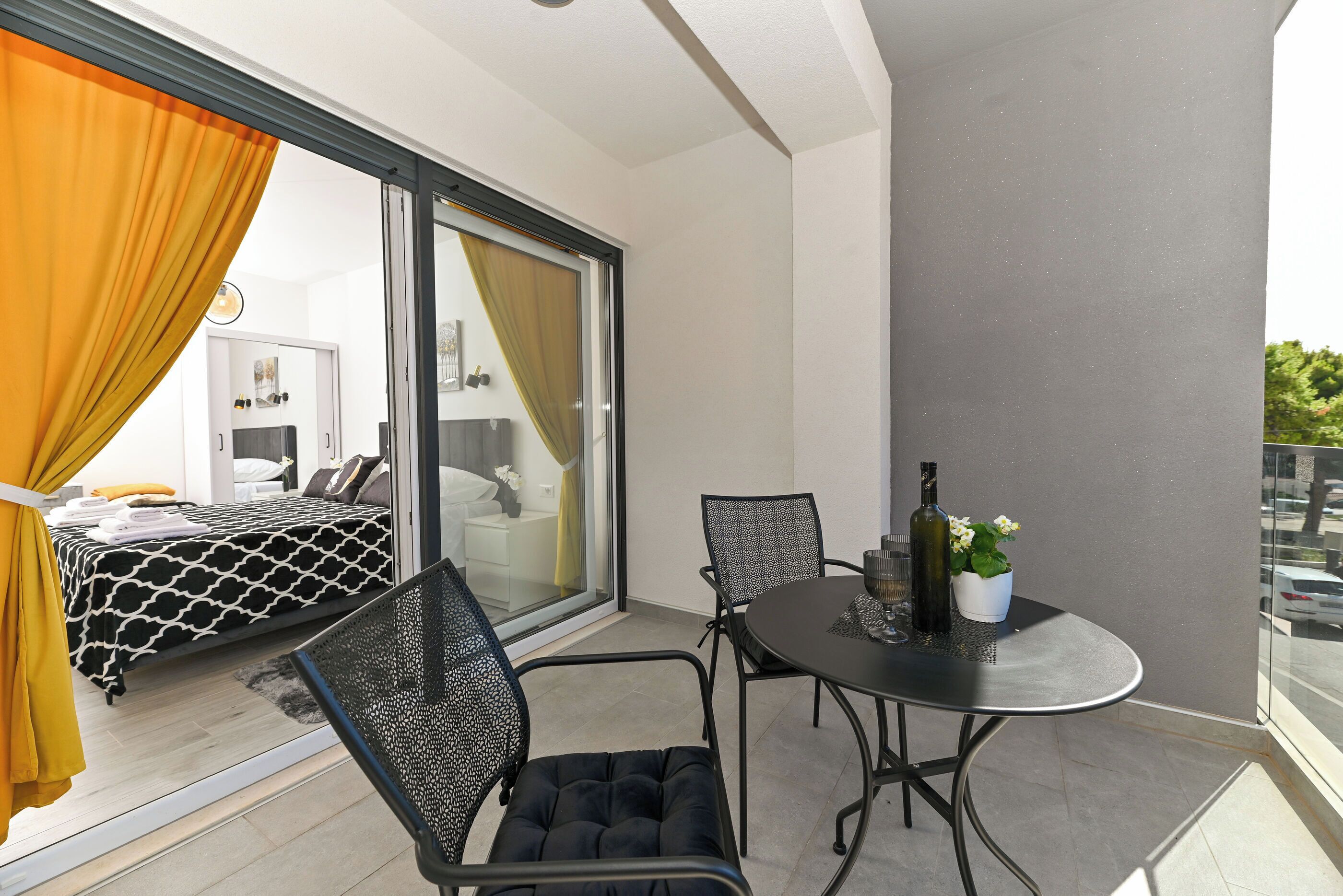 A balcony with a bed, a dining table, and chairs.