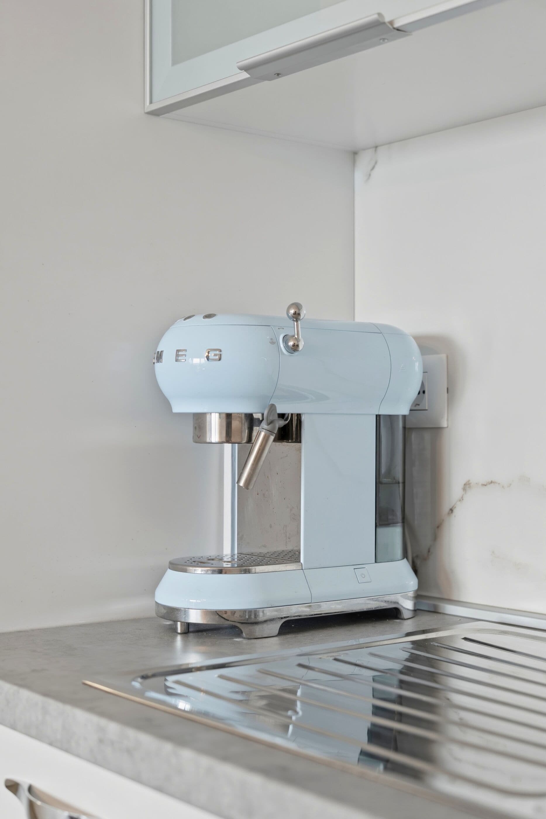 A coffee machine on a countertop with a metal grate below.