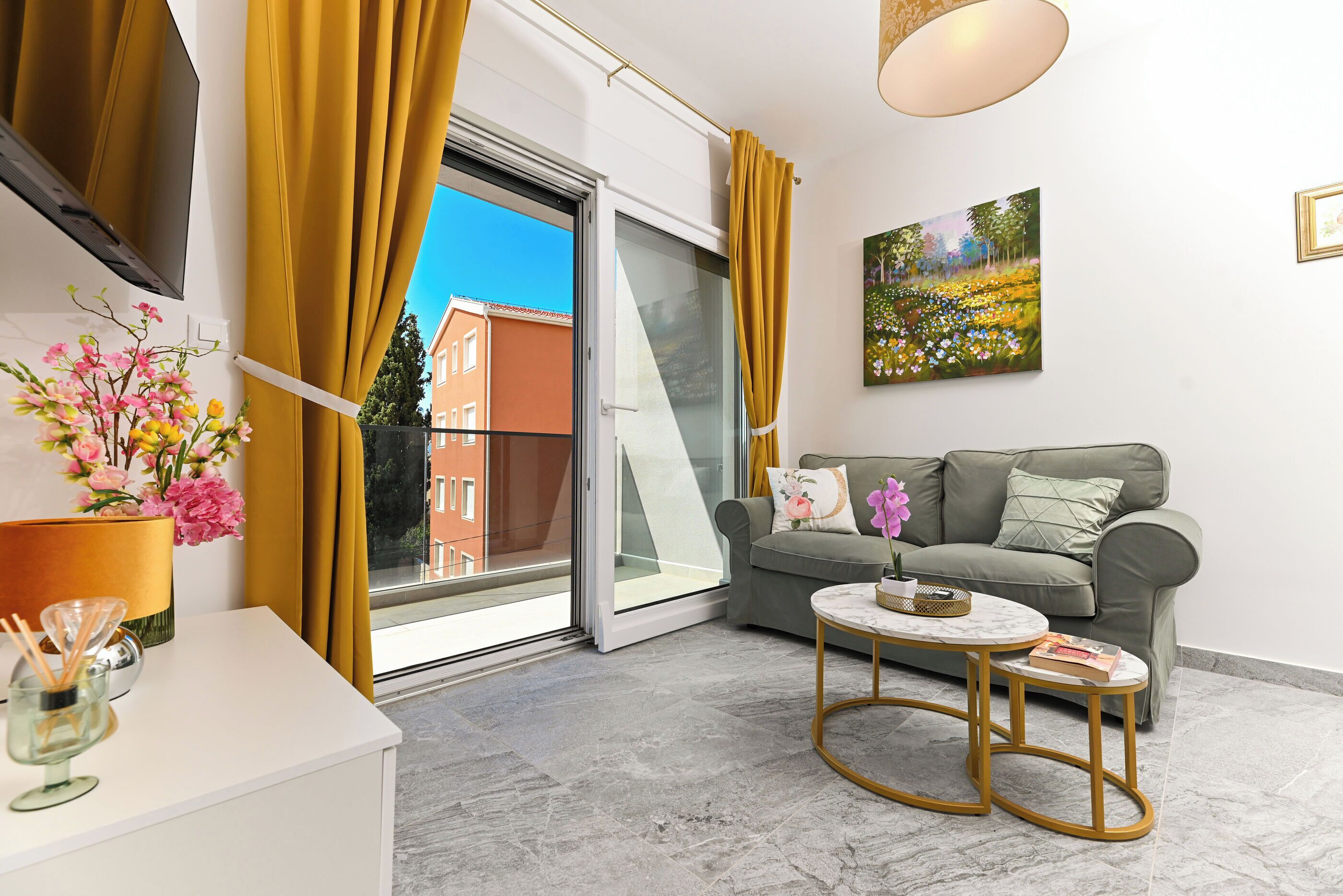 A modern living room with a sofa, a coffee table, and a view through a sliding glass door.