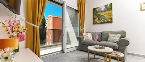 A modern living room with a sofa, a coffee table, and a view through a sliding glass door.