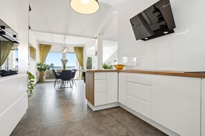 A modern kitchen with white cabinets, a wooden countertop, and a built-in oven. - Apartments Diva (Okrug)