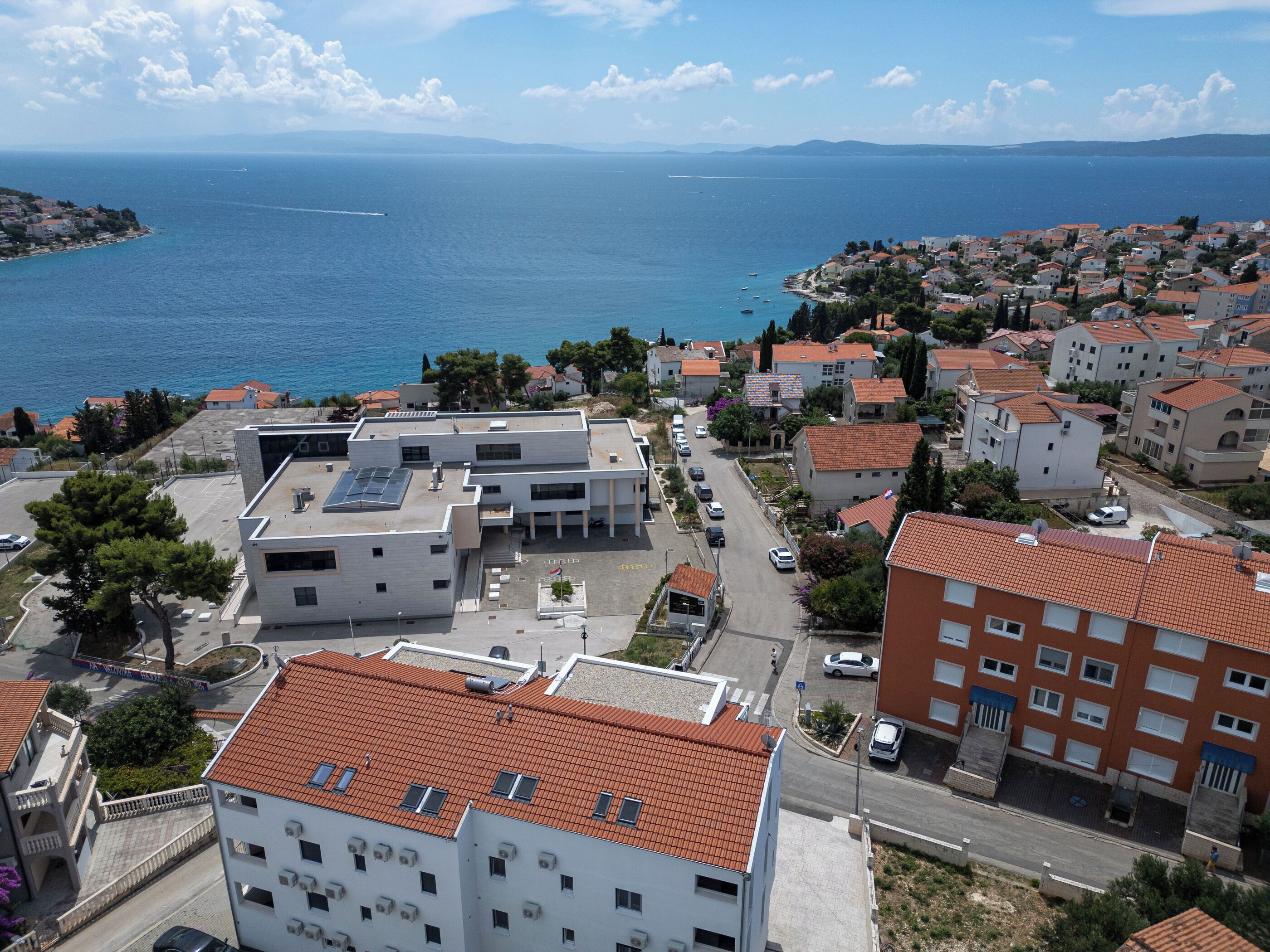 A coastal town with a mix of residential buildings, some with red-tiled roofs and others with white facades.