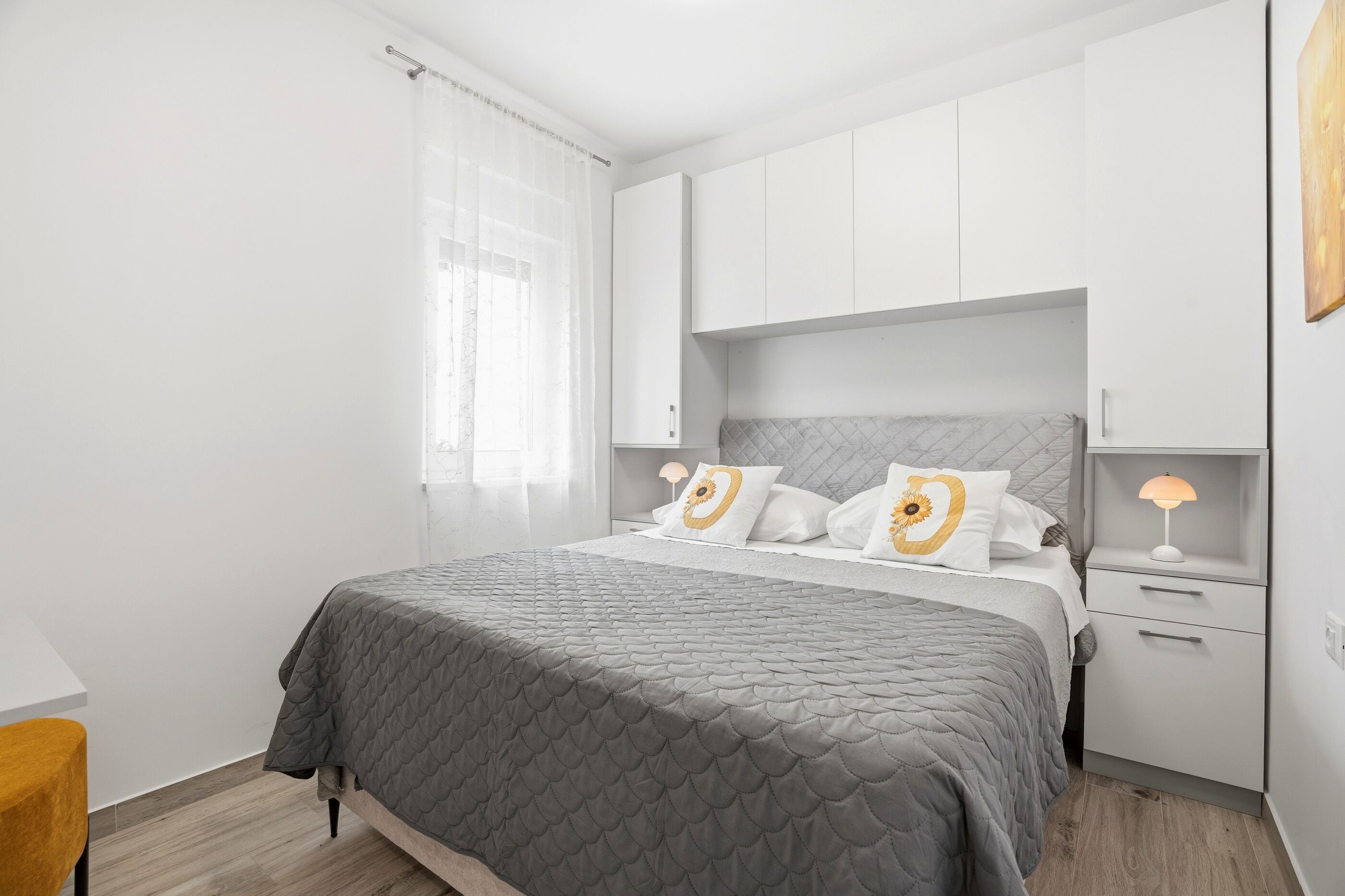 Une chambre à coucher avec un lit, une table de chevet, une lampe et une fenêtre avec des rideaux.