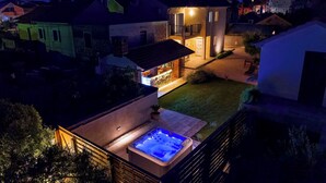 A residential property with a hot tub, a well-lit patio, and a view of neighboring houses. - House Bona (Sukosan)