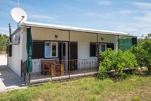 A single-story house with a covered porch, a satellite dish, and a small table with chairs. - House Mirna (Rogoznica)