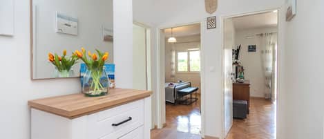 A hallway with a wooden counter and a vase of flowers, leading to a dining area with a table and chairs.