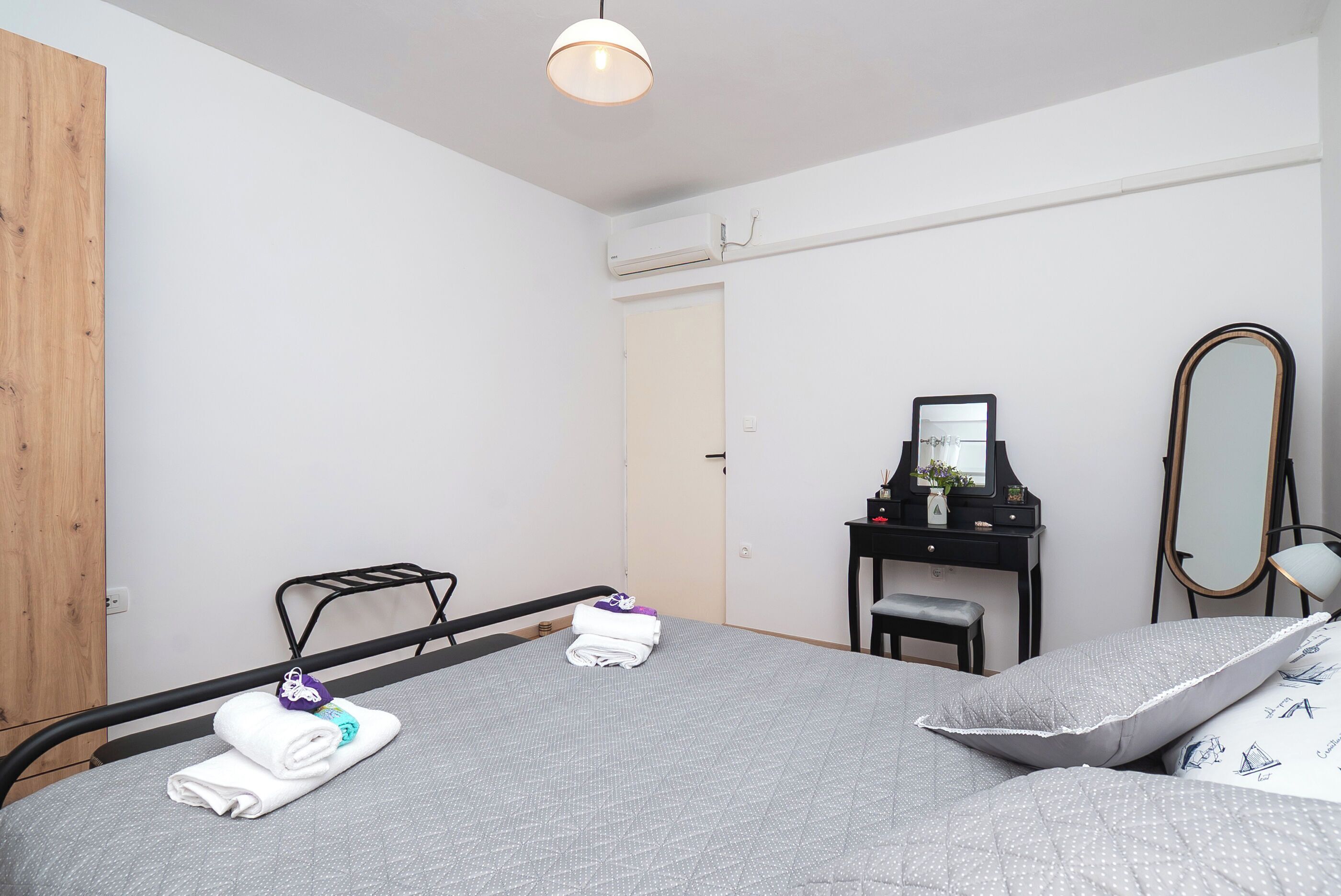 Une chambre bien rangée, avec un lit, un bureau, une chaise, un miroir et une armoire.