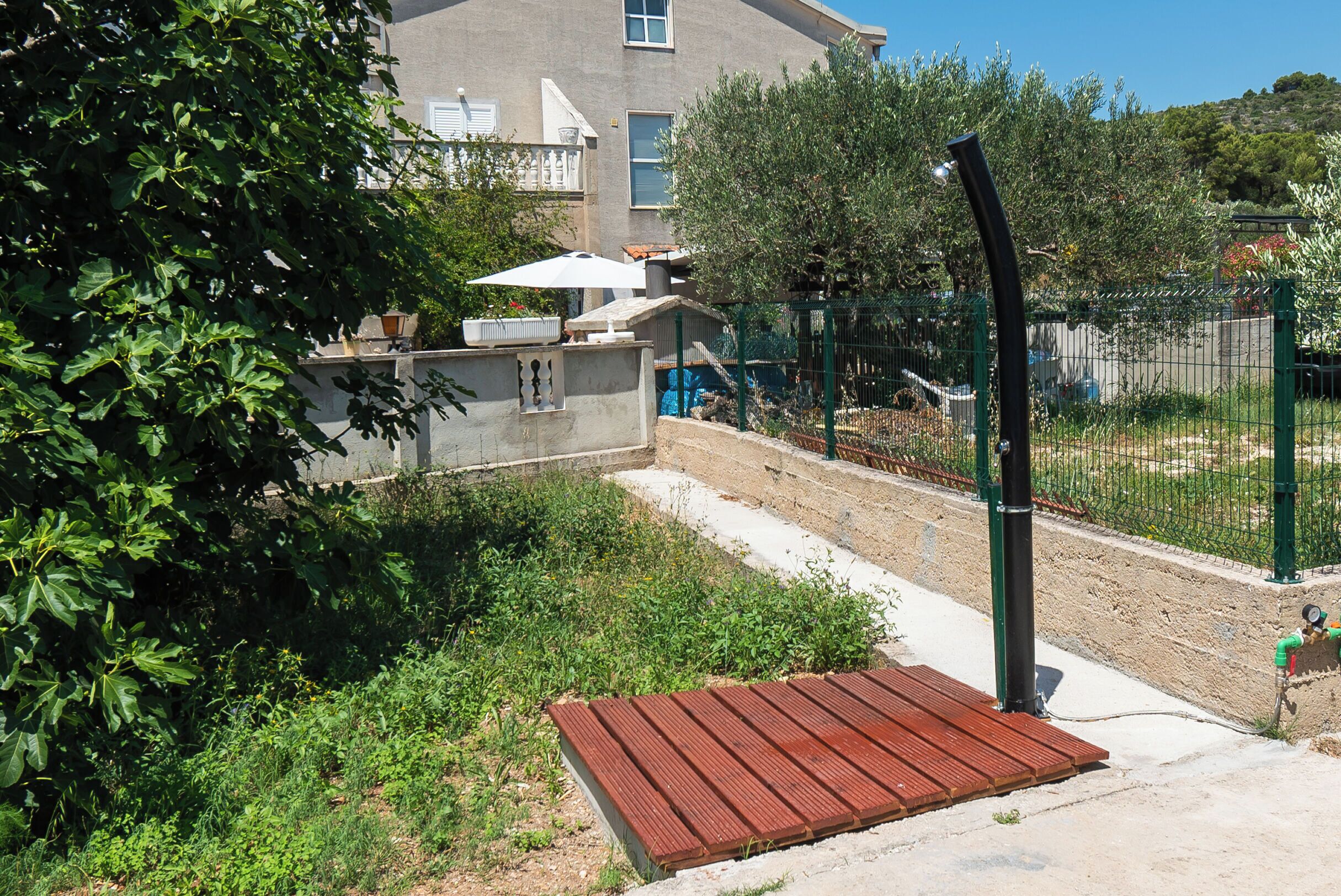A courtyard with a metal bench, a concrete wall, and a green fence.