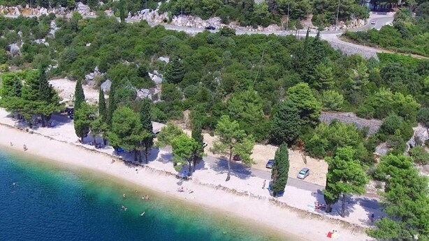An aerial view of a beach with clear turquoise waters, a sandy shore, and dense greenery. - Apartment Leo (Ploce)