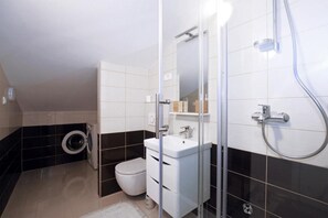 A modern bathroom with a toilet, sink, and shower. - Apartment Leo (Ploce)