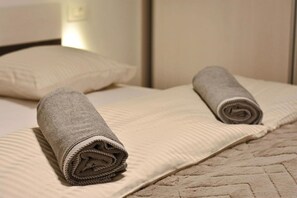 A neatly made bed with two rolled towels and a pillow. - Apartment Leo (Ploce)