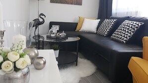 A modern living room with a black leather sofa, a glass coffee table, and a white rug. - House Matenda House (Solin)