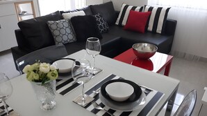 A dining area with a white table set for two, featuring black and white striped placemats, clear glassware, and a vase with white flowers. - House Matenda House (Solin)