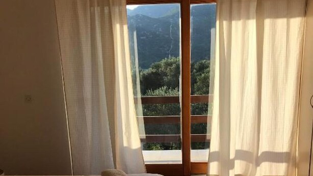 A bedroom with two beds, a wooden floor, and a view of a mountainous landscape through a sliding door. - House Katy (Ploce)