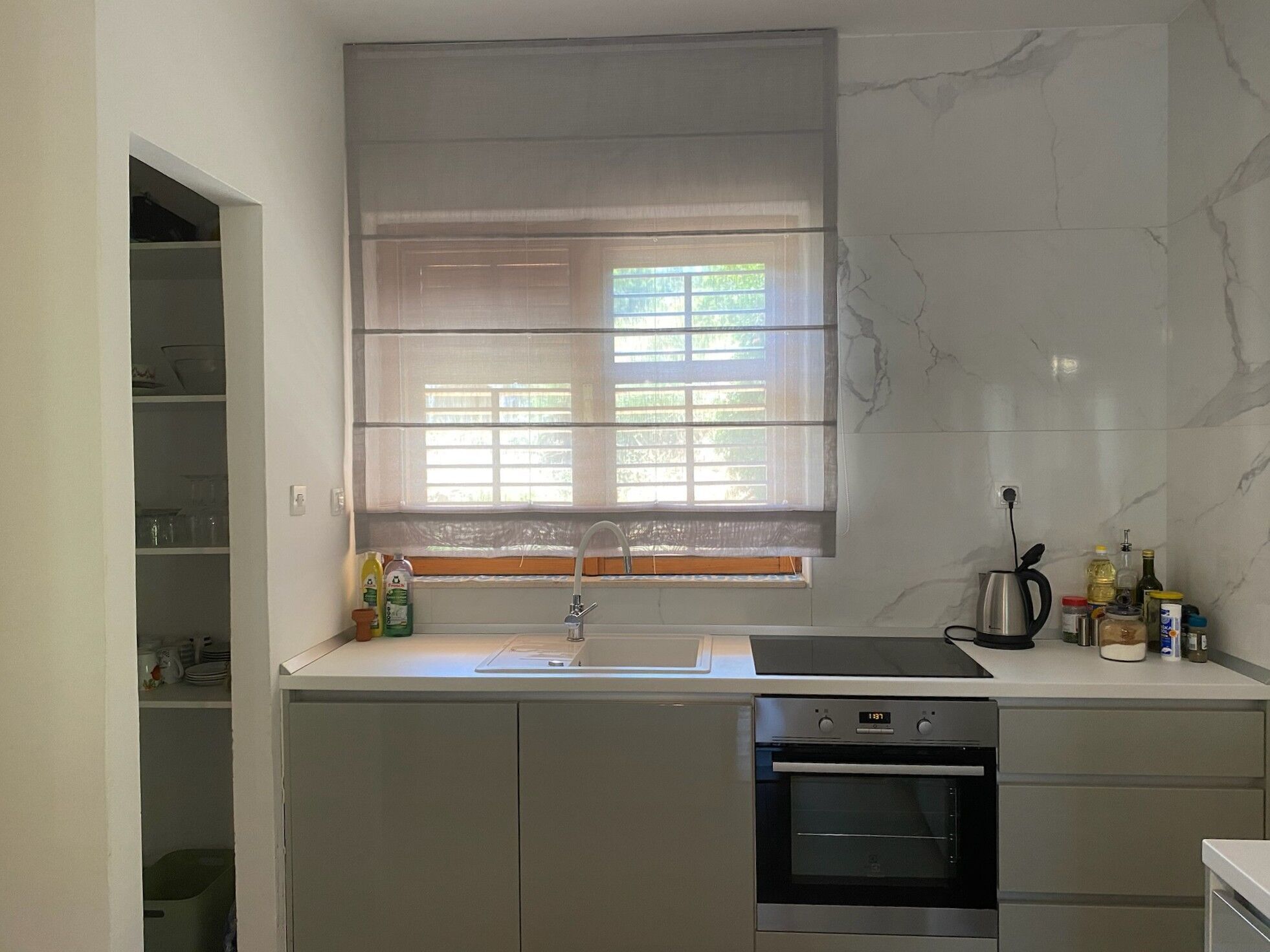 A kitchen with a window, sink, stove, and oven.