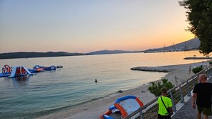 Ein Strand mit freiem Blick auf das Meer, einem Rettungsturm und einer Felsformation im Hintergrund.