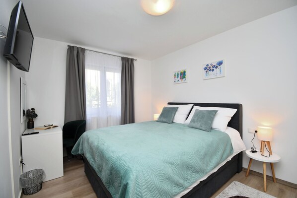Una camera da letto con un letto, una scrivania, una sedia, una TV e una lampada da comodino.