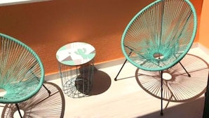 A balcony with two turquoise wire chairs and a small table, overlooking a coastal area with boats and greenery. - Apartments Delfin (Vodice)