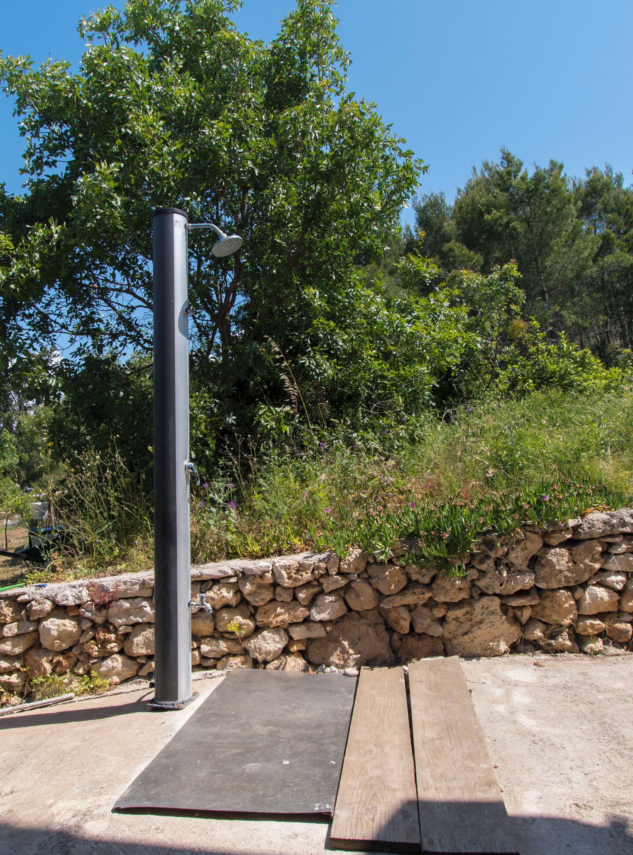 A metal structure with a flat surface, possibly a bench or table, next to a stone wall with vegetation.