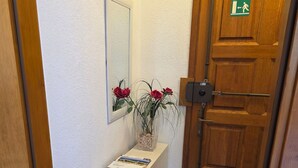 Ein Flur mit einer weißen Konsole, einem Spiegel und einer Holztür mit einem Hinweisschild für den Ausgang.
