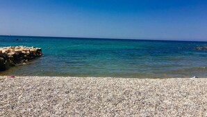 A pebbled beach with clear turquoise water and a rocky breakwater. - Room Nelly (Umag)