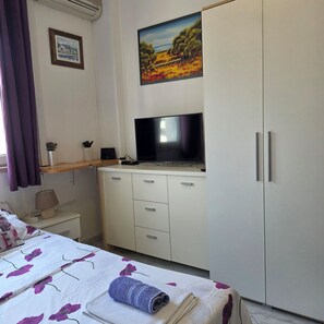 Una camera da letto con un letto, una TV, una scrivania e un armadio.
