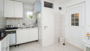 A compact kitchen with white cabinets, a microwave, a sink, and a small refrigerator. - House Garden for two (Vodice)