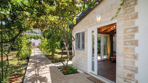 A stone building with a covered outdoor area, a pathway, and a garden. - House Garden for two (Vodice)