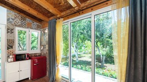 A kitchen with a microwave, a red refrigerator, and patterned tiles on the wall. - House Garden for two (Vodice)