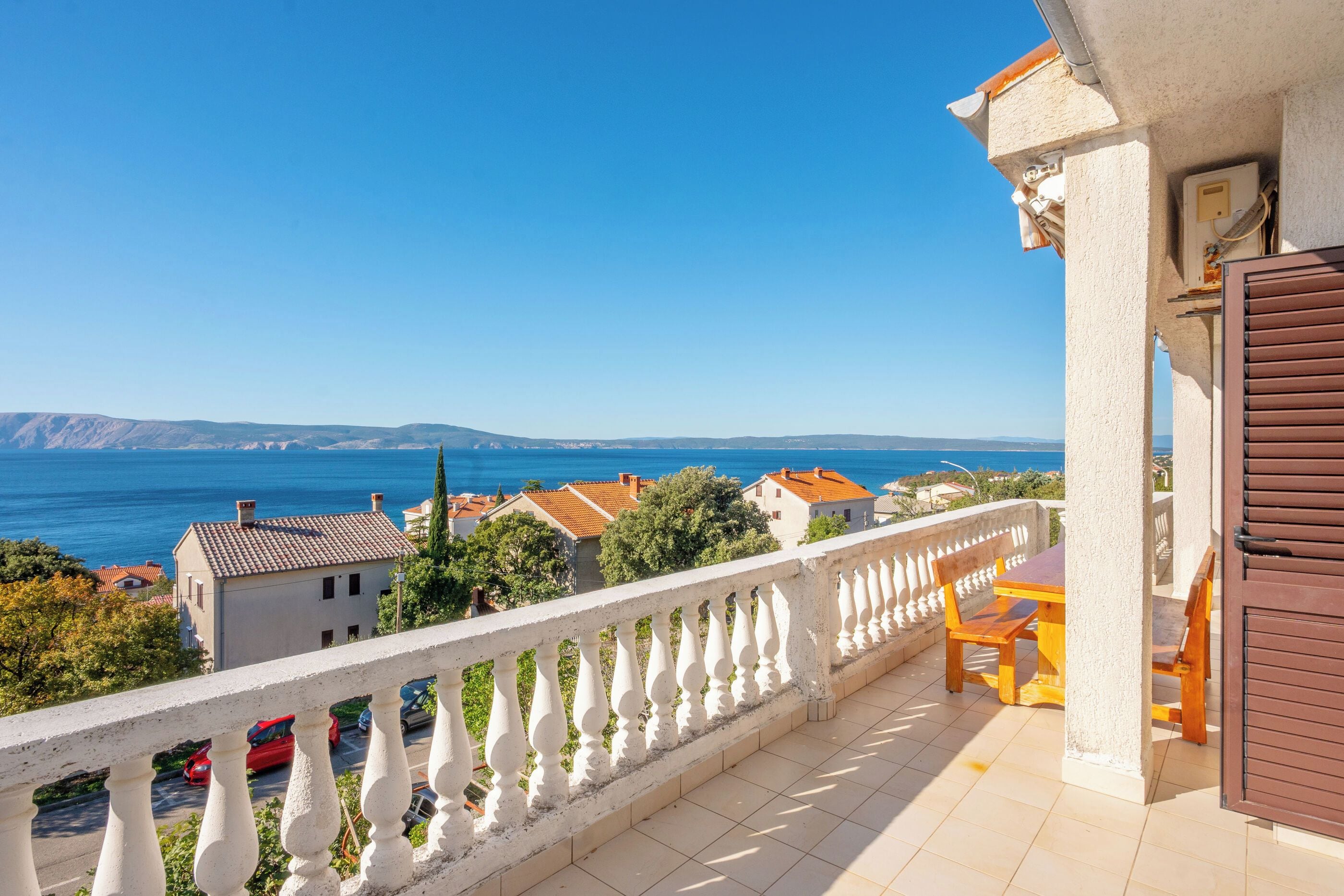 Un balcon avec vue sur la mer et les collines lointaines.