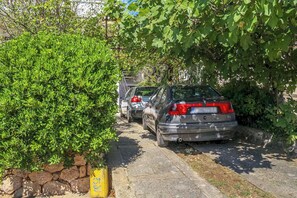 Kapea katu, jonka toisella puolella on parkkeerattuja autoja ja toisella puolella kivimuuri.