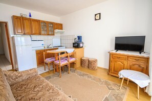 A compact living space with a kitchenette, a dining area, a sofa, and a television. - Apartments Marija (Novi Vinodolski)