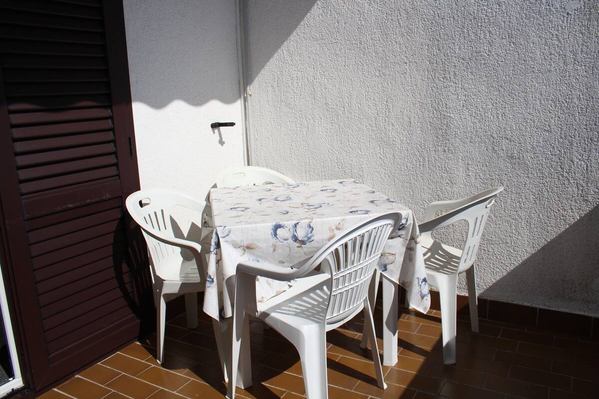 An outdoor patio with a table and chairs, a door, and a textured wall.