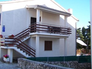 Ein zweistöckiges Gebäude mit Balkon, Treppe und einer Steinmauer.