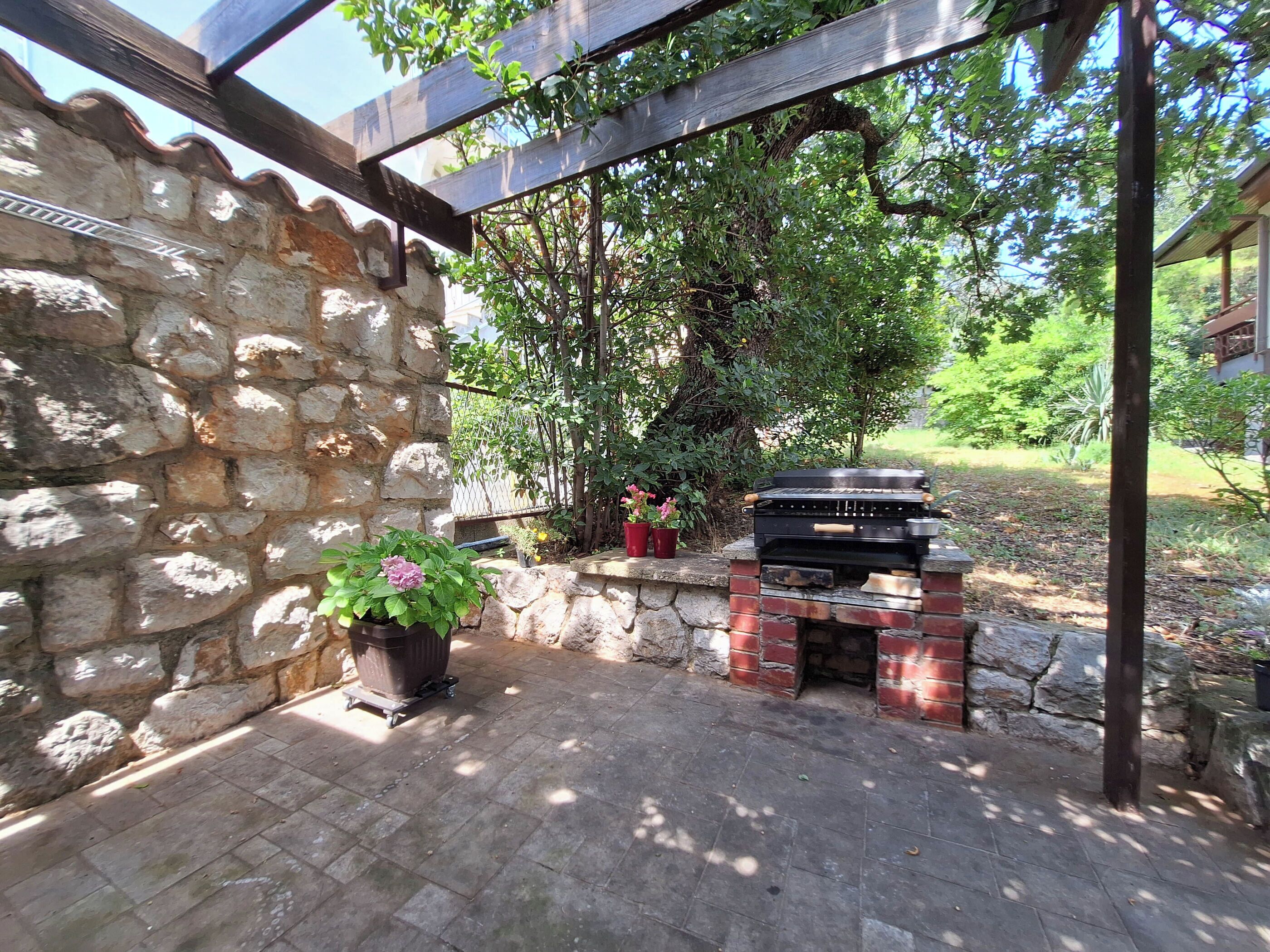 Un muro in pietra, un cancello in mattoni e piante in vaso in un giardino.