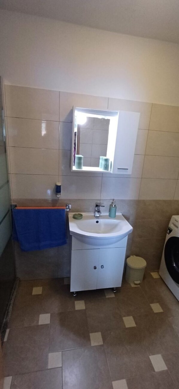 Une salle de bain équipée d’un lavabo, d’un miroir, d’un porte-serviettes et d’une machine à laver.