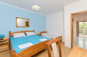 A bedroom with a wooden bed, a small bedside table, a globe, and a mirror on the wall. - Apartments Josip (Vodice)