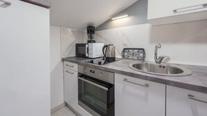 A compact kitchen with a microwave, kettle, and a sink. - Apartments Mil (Karlobag)