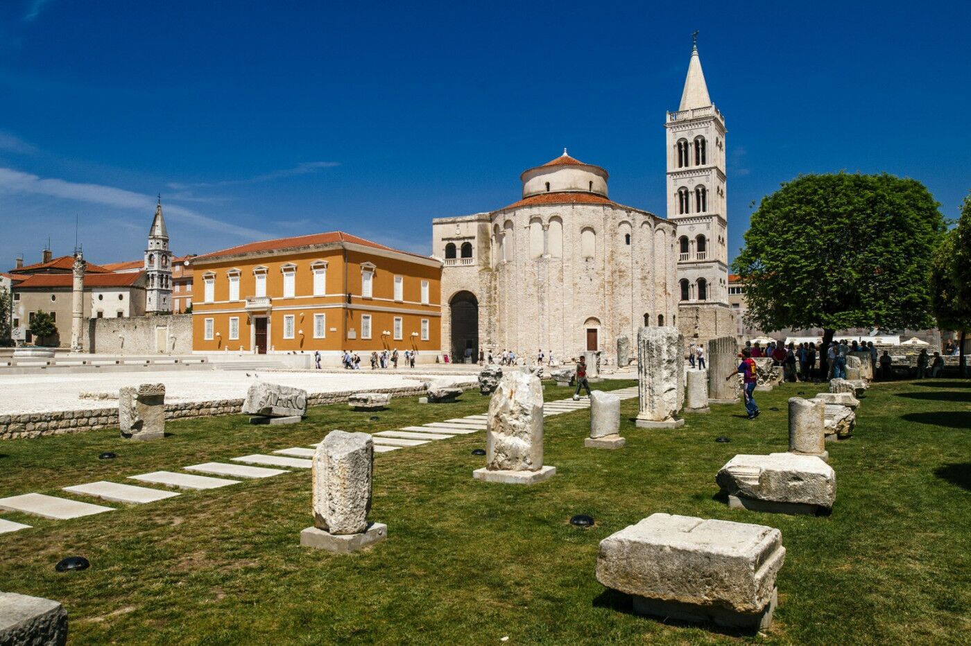 Un sitio histórico con ruinas antiguas, una iglesia destacada y un edificio rojo.
