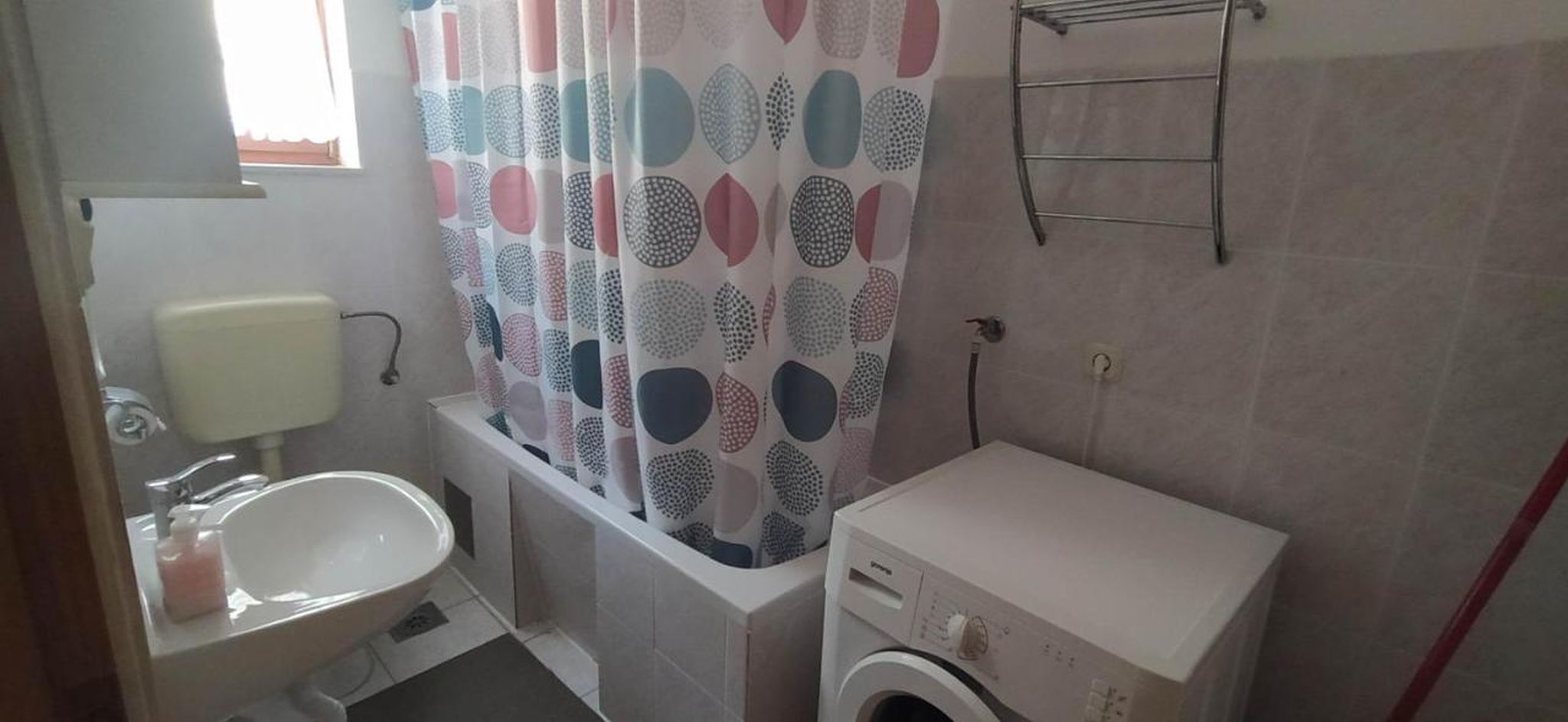 A small bathroom with a toilet, sink, and washing machine.