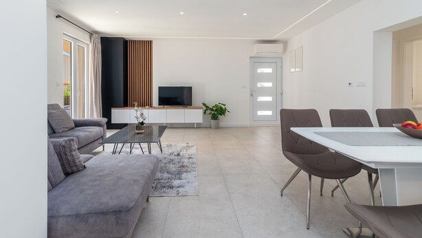 Una sala de estar moderna con un sofá, una mesa de centro, un televisor y un comedor.