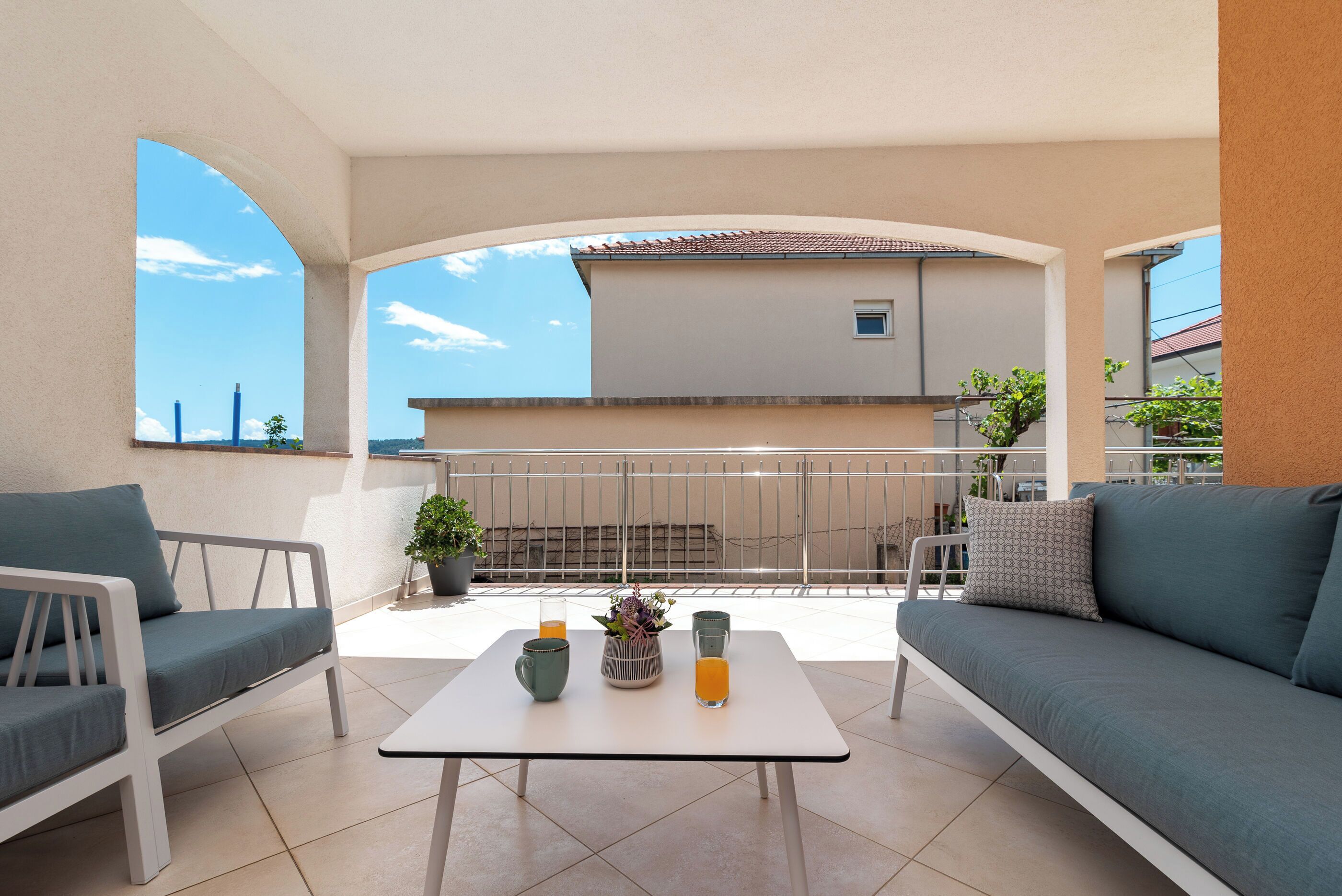 A balcony with a white table, two sofas, and a potted plant.