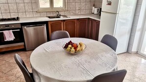 A kitchen with a round table, a bowl of fruit, and a refrigerator. - House Ule 2 (Korčula)
