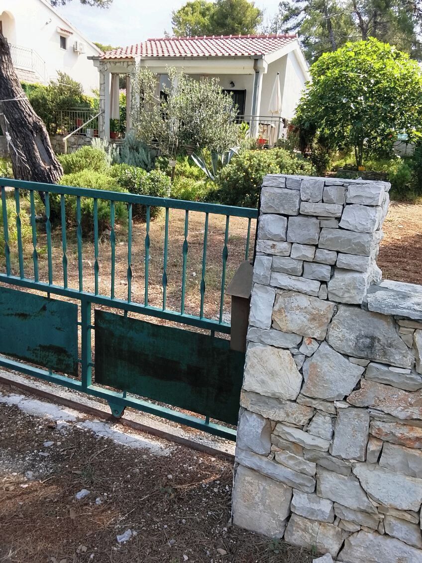 A stone wall and a metal gate in a garden area.