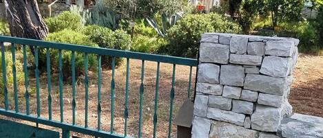 A stone wall and a metal gate in a garden area.