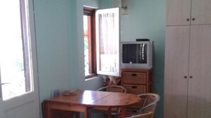 Habitació amb taula de menjador, cadires, televisió i un armari.
